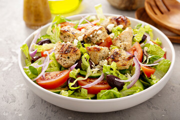 Greek salad with vinaigrette dressing topped with grilled chicken souvlaki