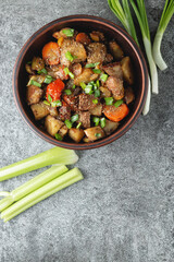 Sticker - Stewed vegetables with spices in an earthen bowl on a dark gray slate or stone background. View from above.