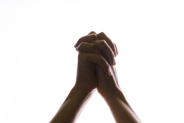 Praying crossed hands on a white background. Light from above. Hands folded in prayer. Hand gestures