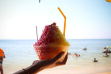 Shaved Ice, Snow Cone, On Hand With Sea Beach Background. Summer And Vacation Concept.