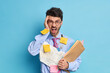Leinwandbild Motiv Irritated office worker exclaims with anger being overloaded with paper work holds folders with documentation wears round spectacles isolated over blue background. Angry employee stands indoor