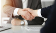 © Iryna - Unknown businessman shaking hands with his colleague or partner above the desk in sunny office, close-up