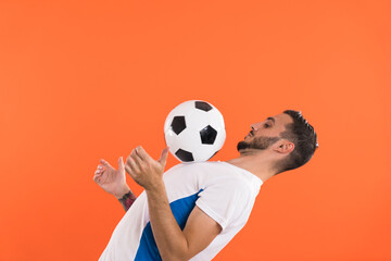 Professional Football player playing with ball isolated on orange background