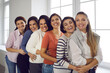 © Studio Romantic - Group portrait of female friends hugging, smiling and looking at camera. Team of happy young women in their 20s and 30s standing in bright office and embracing each other. Concept of unity and support