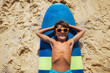 © Sergey Novikov - Happy relaxed boy portrait lay on the surfboard view from above resting wearing sunglasses on the beach