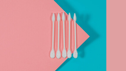 White cotton buds isolated on pink and blue background.