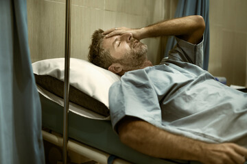 dramatic artistic hospital portrait of attractive and scared man infected by covid19 -  adult male in face mask receiving treatment for coronavirus respiratory desease on bed