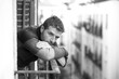 © TheVisualsYouNeed - dramatic artistic portrait of attractive man sad and depressed at home balcony leaning upset feeling worried suffering depression problem looking to city street thoughtful