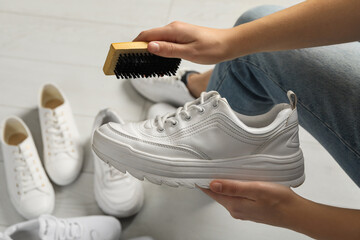 Woman cleaning stylish footwear indoors, closeup. Shoe care accessory