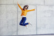 © baranq - Happy woman jumping against concrete wall in the city