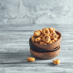 Traditional italian snack taralli or tarallini in wooden bowl over old gray wooden table. Rustic shot of taralli appetizer with copy space. Square crop