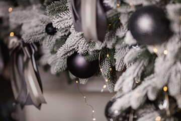 Wall Mural - Black and silver Christmas balls on a snow-covered branch of a Christmas tree.