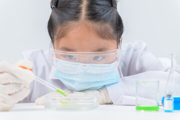 Wall Mural - cute little girl wearing safty glasses making experiment and using dropper in chemical laboratory