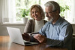 © fizkes - Close up smiling mature man and woman paying online by plastic credit card together, using laptop, shopping at home, satisfied elderly customers making secure internet payment, checking balance