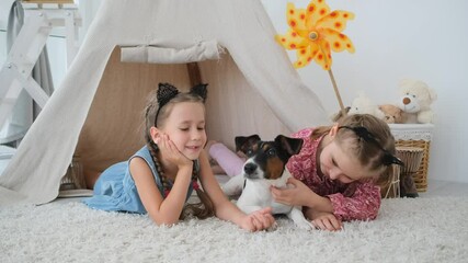 Sticker - Little girls with fox terrier lying in wigwam on kids room floor