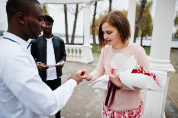 Wedding engagement ceremony with pastor. Multiethnic couple put ring each other. Relationships of african man and white european woman.