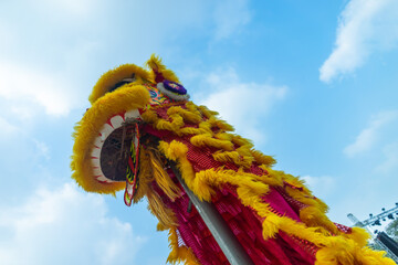 Lion dance - dragon & lion dance street performances. Yellow lion head with blue skies in background.