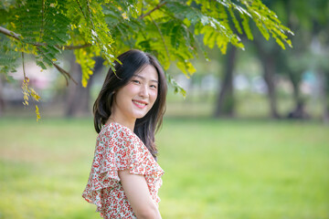 Young beautiful Asian woman enjoying her time on picnic blanket in beautiful natural park