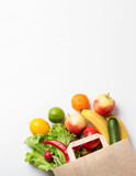 Fototapeta Kuchnia - Vegetables and fruits in a paper bag on a white background with space for text. Online order from a grocery store. The concept of proper nutrition. Food delivery.