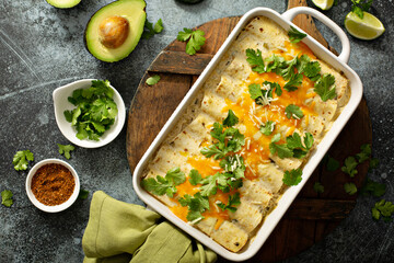 Green enchiladas casserole in a baking dish topped with cheese and cilantro