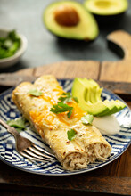 Green Enchiladas On A Plate Topped With Cheese And Cilantro
