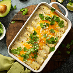 Green enchiladas casserole in a baking dish topped with cheese and cilantro