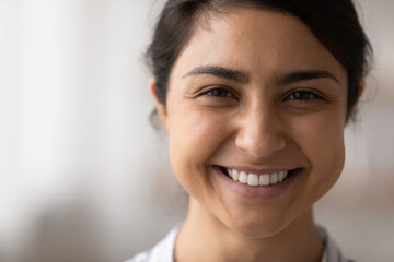 Close up cropped portrait of charming millennial female of indian ethnicity advertising spa beauty facial skin care procedures. Beautiful lady look at camera demonstrate snow white smile. Copy space