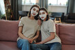 © pressmaster - Two young affectionate brunette females having facial clay mask at home