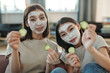 © pressmaster - Two young happy Asian females with clay mask on faces sitting in front of camera