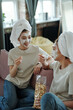 © pressmaster - Young casual twins with towels on heads and clay mask on faces having popcorn