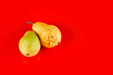 Fresh ripe pears isolated on red background