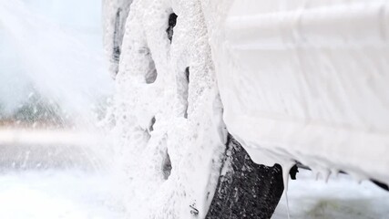 Wall Mural - Close up view of spraying cleaning foam on car wheel during car wash