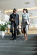 © pressmaster - Young Asian businesswoman with folded laptop listening to mature male colleague