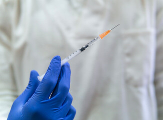 Doctor, nurse, scientist, researcher hand in blue gloves holding flu, measles, coronavirus, covid-19 vaccine disease preparing for human clinical trials vaccination shot, medicine and drug concept.