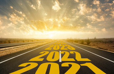 The word 2022 written on highway road in the middle of empty asphalt road at golden sunrise