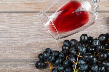 A wine glass with a bunch of red grapes on the table