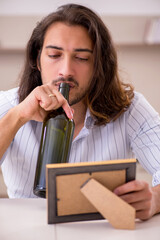 Poster - Young man drinking alcohol at home in unhappy love concept