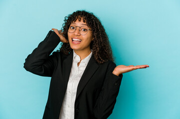 Young african american afro woman isolated holds copy space on a palm, keep hand over cheek. Amazed and delighted.