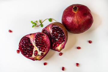 Whole and two halves of juicy ripe pomegranate on a white background close-up.