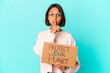 © Asier - Young hispanic mixed race woman holding a protect our planet cardboard keeping a secret or asking for silence.