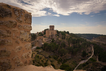 Wall Mural - Landscape with the fortified city of Alarcon with its watchtowers and the castle on top of the hill on a cloudy day, Cuenca, Spain