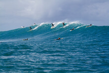 A Group Of Surfers Riding A Wave In Hawaii