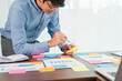 © snowing12 - Businessman stick colorful notes to brainstorming on the table working on new project to share idea to thinking how to planning new case