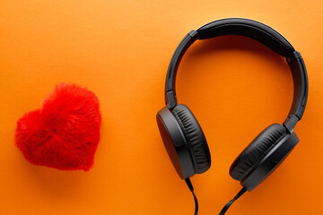 Red heart and black headphones on a orange background. Love music lifestyle concept. Valentine's Day