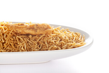 Wall Mural - Indian spicy snacks (Namkeen) - Bikaneri Besan Bhujia in a white oval-shaped plate, made with chickpea flour (Besan), side view, against the white background.