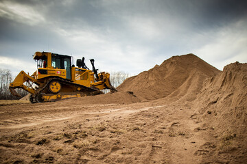 Wall Mural - A yellow bulldozer pushes a full load of material into a pile.