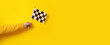 checkered flag in hand over yellow background, panoramic image