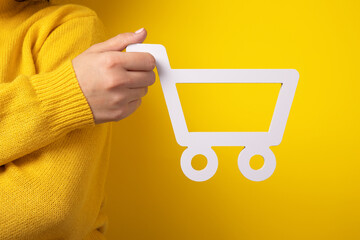 shopping trolley symbol in hand over yellow background