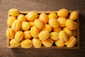 Wall Mural - fresh apricots in a box on a wooden table, top view