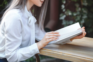 Canvas Print - Beautiful woman reading blank book in cafe outdoors